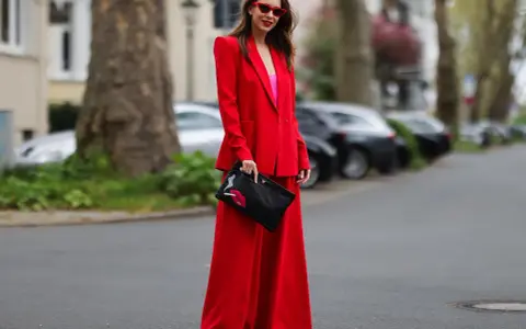 Frau in rotem Hosenanzug mit pinkem Top und Clutch mit Lippenmotiv. Was passt zu roter Hose? Dieser Look zeigt es!