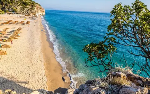 Piękna plaża w Albanii z turkusową wodą i rzędami parasoli. Ceny wakacji w Albanii są przystępne, a widoki zachwycające.