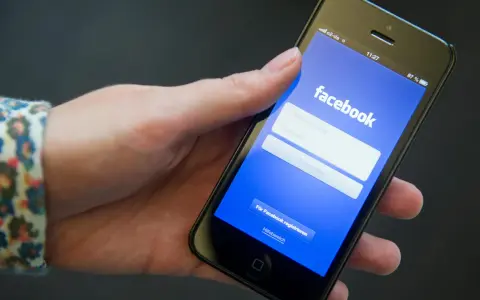 Eine Hand hält ein Smartphone mit der Facebook-Anmeldeseite.