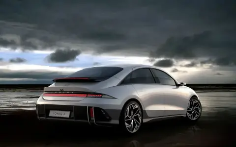 Srebrny Hyundai Ioniq 6 na plaży pod pochmurnym niebem.