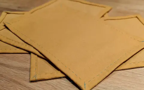 Serviettes de table en tissu ocre, finitions soignées. Idéal pour un tuto serviette de table facile à réaliser.