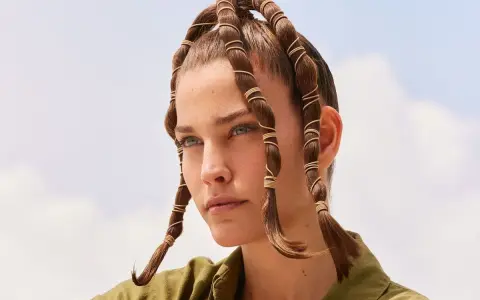 Coiffure d'été audacieuse avec des mèches torsadées et enroulées de fils dorés, rappelant des tentacules aériens sous un ciel bleu.