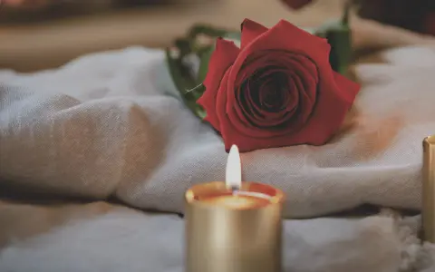 Czerwona róża i płonąca świeca na lnianym materiale. Idealne do samodzielnego wykonania rytuału miłosnego.