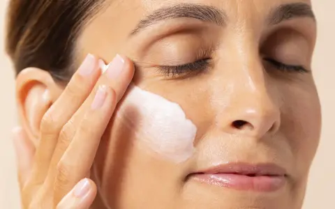 Application d'une crème hydratante contenant de l'acide polyglutamique sur le visage d'une femme.