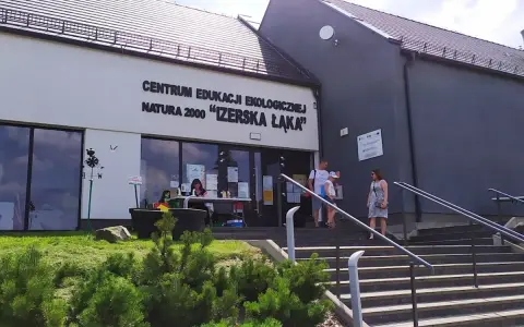 Centrum Edukacji Ekologicznej Natura 2000 "Izerska Łąka" zaprasza. Rodzina wchodzi po schodach do budynku.