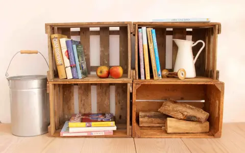 Alte Weinkisten-Ideen: Bücher, Äpfel, eine Kanne und Holzscheite schaffen rustikales Flair.
