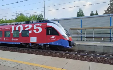 Czerwony pociąg Kolei Małopolskich z numerem 1025 na bocznym panelu, gotowy do podróży z Kielc do Krakowa, stoi na peronie.