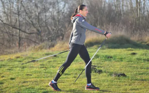 Kobieta w stroju sportowym ćwiczy nordic walking, używając kijków. Widać, jakie kije do nordic walking są lekkie i wygodne.