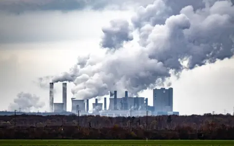 Rauchschwaden steigen aus einem Kraftwerk auf und symbolisieren die historischen CO2-Emissionen, die die Umwelt belasten.