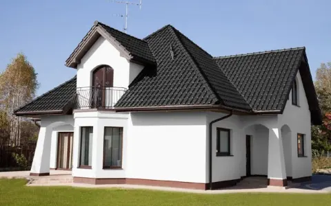 Biały dom z ciemnym dachem. Czy to kolor ral 7016? Elegancka biel ścian kontrastuje z grafitową dachówką.