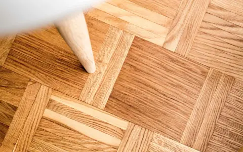 Ett vackert parkettgolv i ek, redo för renovering. En vit möbel står på golvet.