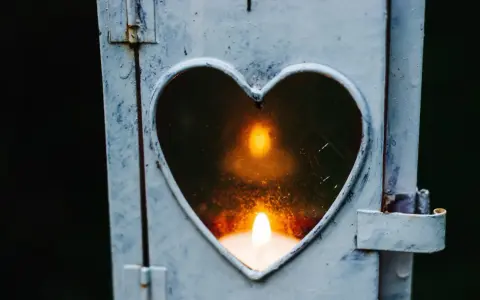 Kerze in Herzform leuchtet. Ein Symbol der Erinnerung an die gestorbene Oma.