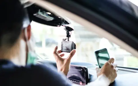 Mann installiert Dashcam im Auto, ADAC-Mitglieder profitieren von sicherer Fahrt.