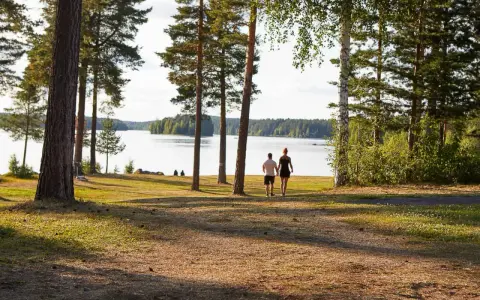 Ett par promenerar hand i hand vid en sjö, en idyllisk plats som påminner om det första camp ansia.