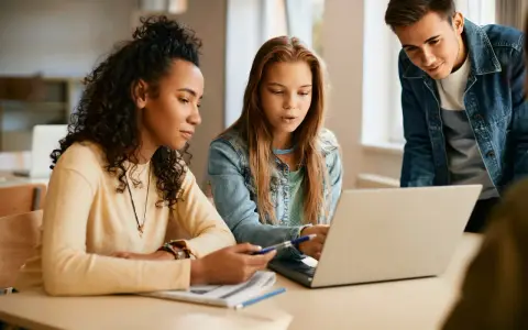 Uczniowie technikum artystycznego w Warszawie pracują nad projektem na laptopie.