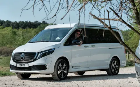 Vit eldriven husbil från Tonke parkerad på grusväg. En man med solglasögon sitter bakom ratten.