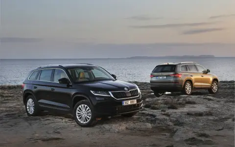 Dwa SUV-y Skoda Kodiaq 2024 na skalistym wybrzeżu. Jeden czarny, drugi w kolorze złota.