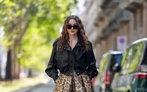 Frau mit langen Haaren trägt eine Lederjacke und einen auffälligen Leo Rock. Sie kombiniert den Leo Rock mit lässiger Eleganz.