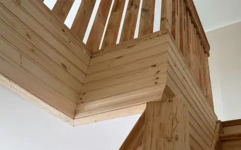 Detalles de la escalera con molduras de madera en la pared, creando un acabado rústico y acogedor.