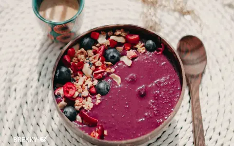 Fruchtige Acai-Bowl mit Blaubeeren, Granola und Beeren – perfekt, wenn du deine eigene Bowl selber machen möchtest. Dazu eine Tasse Kaffee.