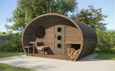 Fasssauna aus thermisch modifiziertem Holz mit runden Fenstern und Holzstapel.