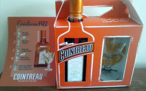 Zestaw Cointreau z kieliszkiem i instrukcją przygotowania drinka Cointreau Fizz. Ten pomarańczowy likier, znany jako Cointreau triple sec, to klucz do orzeźwiających koktajli.