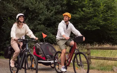 Para wycieczka rowerowa z dzieckiem w przyczepce. Zastanawiasz się, jakie buty na rower będą najlepsze? Oni wybrali wygodne sportowe obuwie.