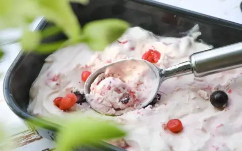 Glace au yaourt italienne aux fruits rouges, servie dans un bac avec une cuillère. Parfait pour une recette facile et rafraîchissante.