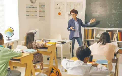 Nauczycielka tłumaczy zadanie z fizyki przy tablicy, dzieląc się wiedzą i doświadczeniem z uczniami.