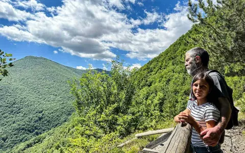 Un uomo e una bambina ammirano il panorama sui sentieri di Roccaraso, immersi nel verde lussureggiante delle montagne.