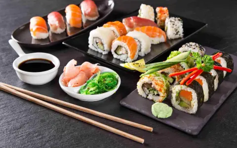 Pyszne sushi, w tym uramaki, z łososiem i awokado, podane z imbirem, wasabi i sosem sojowym.