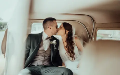 Para młoda całuje się w samochodzie. To symboliczny moment, który może oznaczać zmianę nazwiska po ślubie i początek wspólnej drogi.