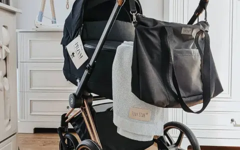 Stylowe wyposażenie wózka dla noworodka: czarna torba i miękki kocyk Tiny Star.