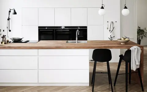Un plan de travail en bois chaleureux contraste avec les meubles de cuisine blancs. Quelle couleur de plan de travail pour une cuisine blanche ? Le bois est une option parfaite.