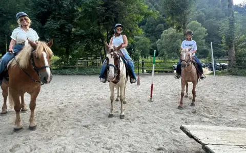 Tre donne si godono una passeggiata a cavallo in Lombardia, con un uomo che le osserva.