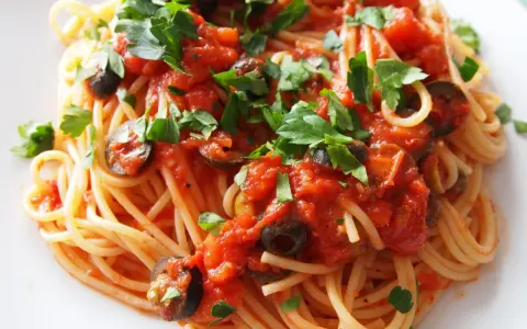 Pyszne spaghetti puttanesca przepis: makaron z sosem pomidorowym, oliwkami i natką pietruszki.