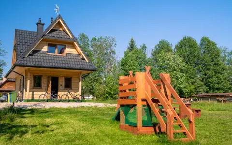Drewniany domek w Bukowinie Tatrzańskiej z placem zabaw i rowerami przed wejściem. Idealne miejsce na rodzinne wakacje.