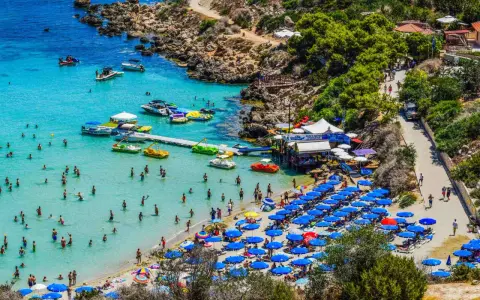 Piękna plaża na Cyprze, pełna ludzi kąpiących się i opalających. Czy na Cypr potrzebny jest paszport z Polski? Nie, wystarczy dowód osobisty.