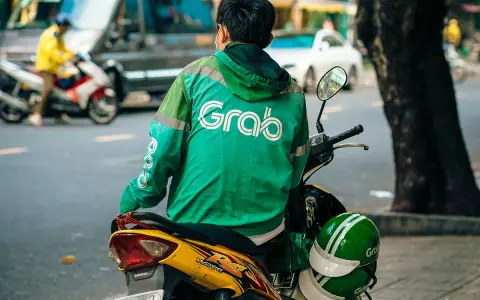 Fahrer mit Grab-Jacke wartet auf seine nächste Fahrt in Vietnam.