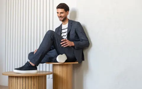 Uśmiechnięty mężczyzna w granatowym garniturze i białej koszulce w paski, idealny przykład dress code smart casual.