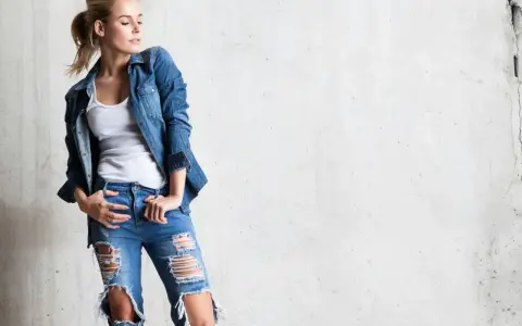 Stylowa blondynka w rozdartych jeansach i jeansowej koszuli. Inspiracja, jak nosić koszulę do jeansów.