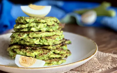 Pila di rosti di zucchine dorati, guarnita con spicchi di uovo sodo. Un piatto leggero e gustoso, perfetto per ogni pasto.