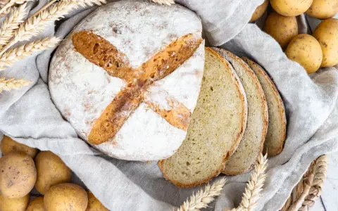 Frisch gebackenes Kartoffelbrot, aufgeschnitten und mit Kartoffeln und Weizenähren dekoriert. Ein tolles Rezept für Kartoffelbrot!
