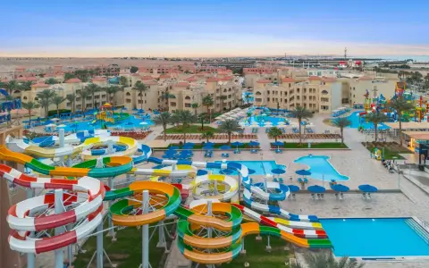 Kolorowe zjeżdżalnie wodne i baseny w Albatros Aqua Park, otoczone palmami i hotelami, zapraszają do zabawy.