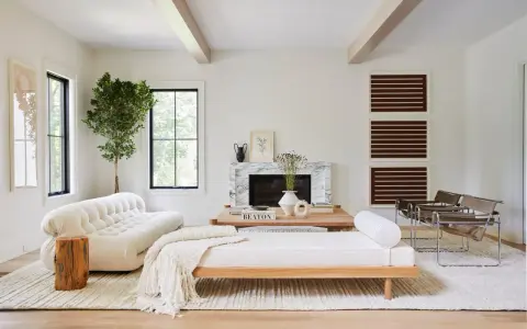 Elegante salón blanco y madera oscura. Sofá blanco texturizado, chaise longue de madera clara, chimenea de mármol y sillas de cuero.