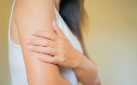 Une femme se gratte le bras, évoquant les démangeaisons cutanées liées à la ménopause.