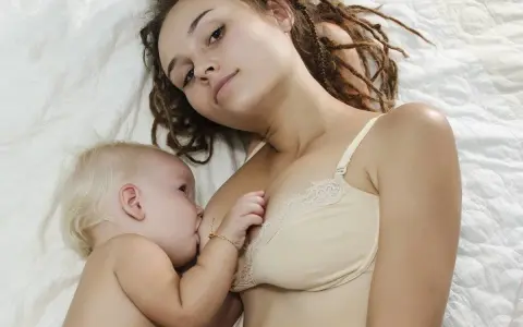 Mama z dredami karmi piersią niemowlę. To piękny moment bliskości, choć nie jest to karmienie piersią 10 latka.