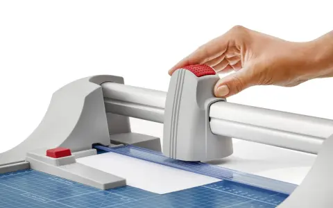 Mano operando una guillotina o cizalla para cortar papel con precisión.