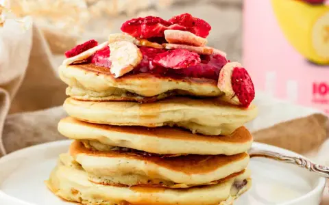 Stapel fluffiger Pfannkuchen mit gefriergetrockneten Erdbeeren und Bananen, perfekt für gesunde Snacks selber machen.