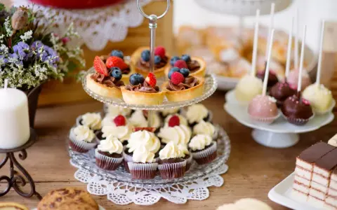 Stół z ciastkami, babeczkami, tartaletkami z owocami i cake pops.
